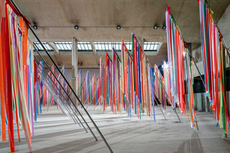 Flagpoles covered in colourful ribbons on a landscape of sand