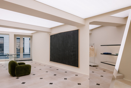 creme store interior decorated with a contemporary black painting, a chair and a mirror sculpture