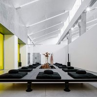 low black wooden modular table set in a concrete and white wall venue with a yellow window.