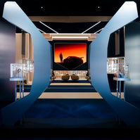 metal sculpture set in a low-light environment in front of an open space with seating areas