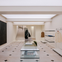 store interior featuring a richard serra painting on the wall, custom-cut floor tiles and a white backlit ceiling.