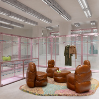 brown leather chairs and table set on a colourful carpet, surrounded by pink metal and glass pieces of furniture