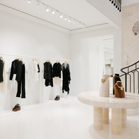 Stone table display set in a white clothing store near a staircase