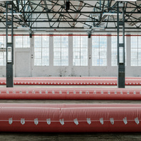 row of flood barriers inside an industrial warehouse in front of big windows