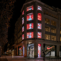 Building facade and store windows at night with screens showing media