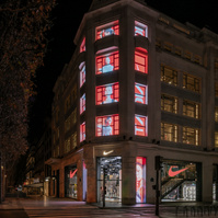 Building facade and store windows at night with screens showing media