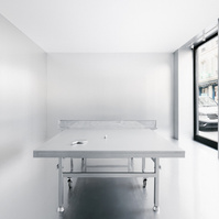 chrome pingpong table set in a room with reflective metal walls and a white ceiling.