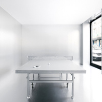 chrome pingpong table set in a room with reflective metal walls and a white ceiling.