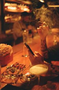 detail of customer smoking a cigar at a bar