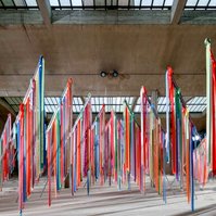 colourful ribbons attached to metal flagpoles on white sand