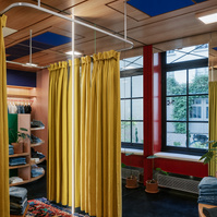 open mirrored fitting-room with a yellow fabric curtain and a carpet on the floor. wooden ceiling with Mondrian-like patterns.