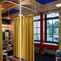 open mirrored fitting-room with a yellow fabric curtain and a carpet on the floor. wooden ceiling with Mondrian-like patterns.