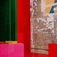 tunnel made of a green grid-like material, red wall and floor, pink piece of furniture