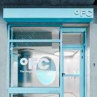 grey metal and concrete interior with touches of glossy blue lacquer seen through storefront windows