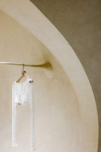 white piece of clothing hanging from a custom made rail coming out of a rounded wall covered in limestone clay. 
