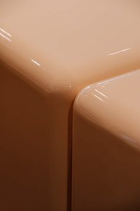 detail of a peach-coloured soft edged glossy piece of furniture