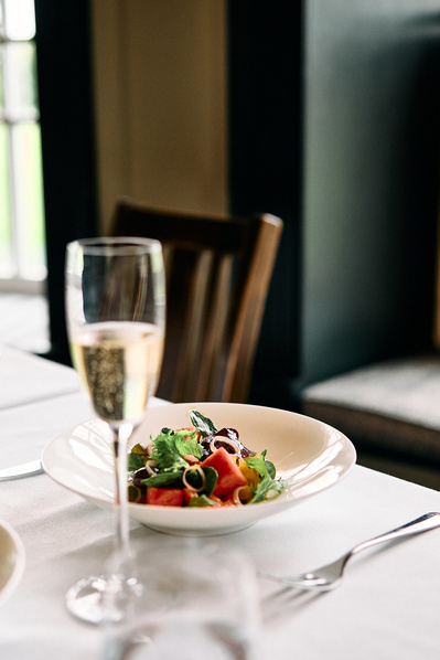 A close up photograph of a fresh meal and glass of white wine in a restaurant. 