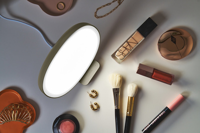A top down photograph of a Lumie lamp surrounded by makeup and jewellery. 