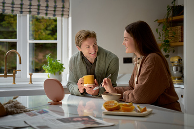 A man and woman having breakfast in their kitchen. 