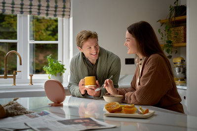 A man and woman having breakfast in their kitchen. 