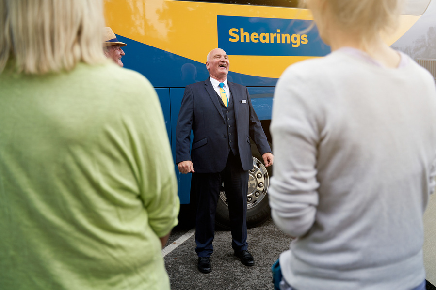 a person in a suit and tie standing next to a bus