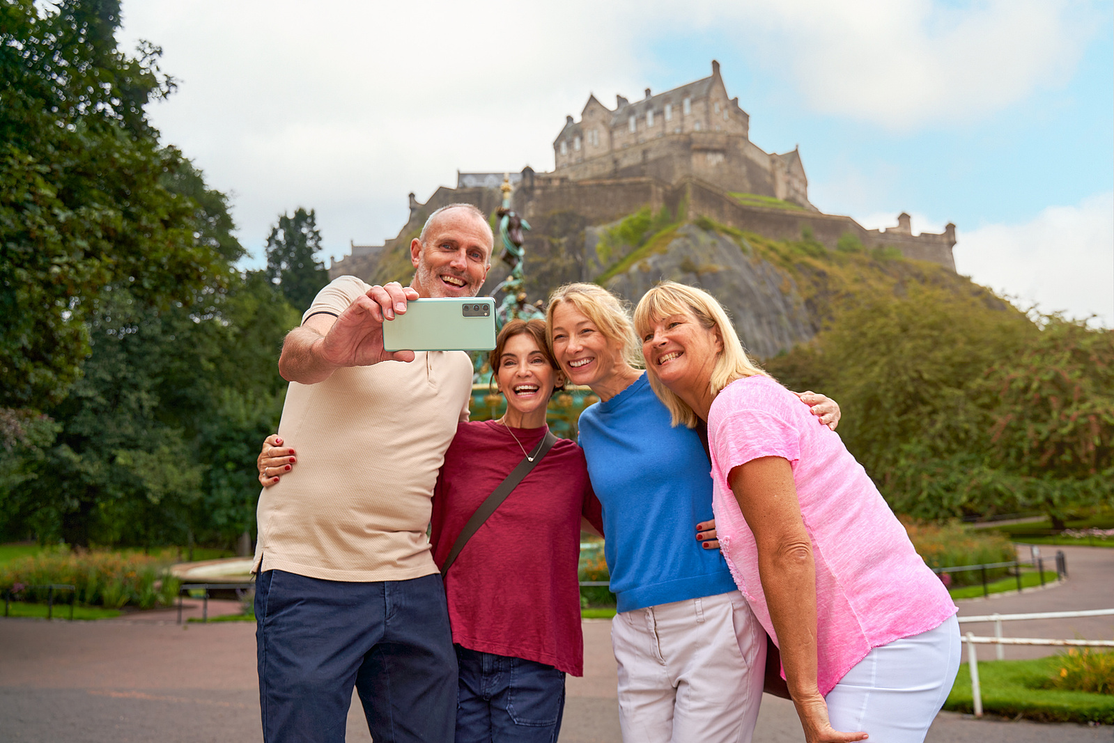 a group of people taking a selfie in front of edinburgh castle