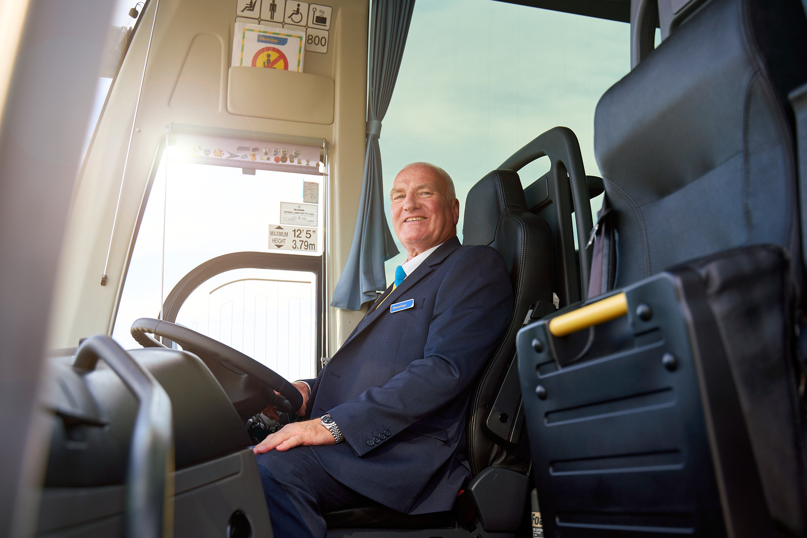 a person in a suit sitting in the driver's seat of a bus