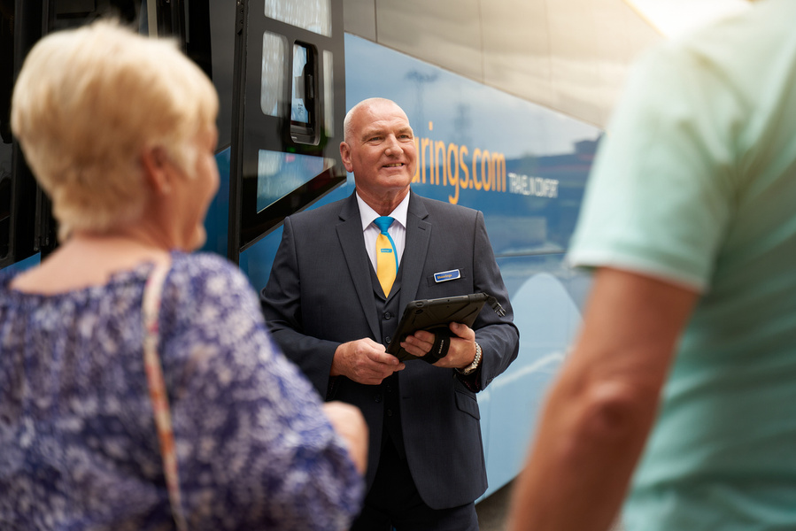 a person in a suit and tie standing next to a bus