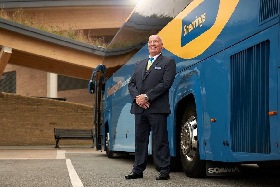 a person in a suit and tie standing next to a bus