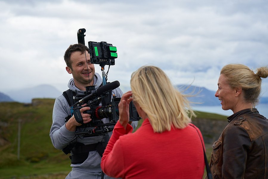 a person with a video camera filming two people. 