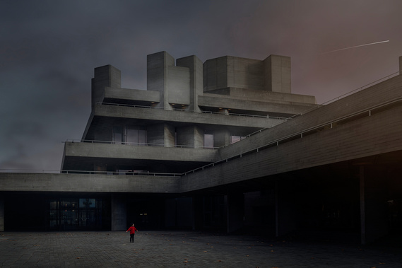 A young Chinese boy in a red top plays alone amongst brutalist architecture. 