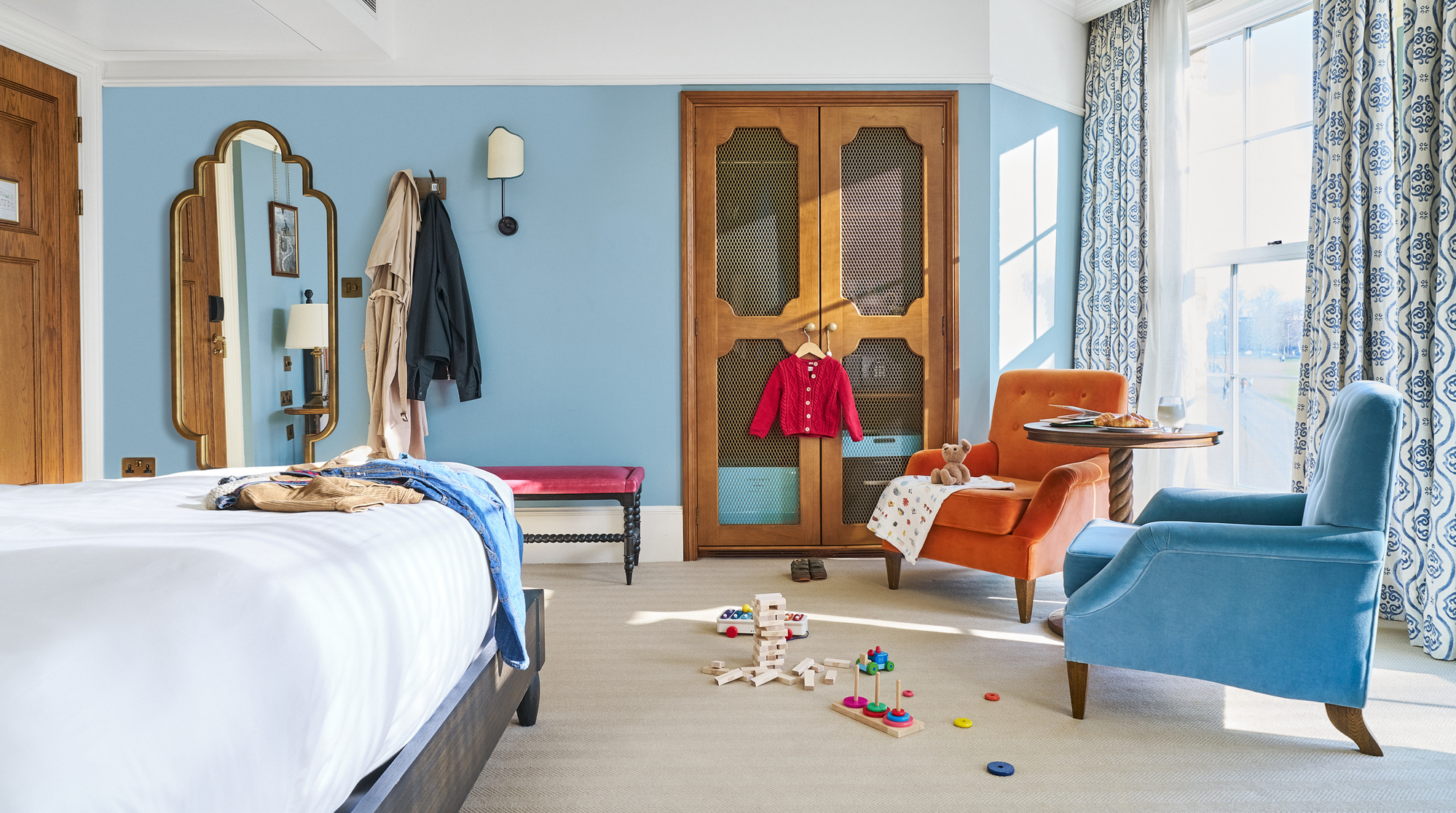 A bright and airy hotel room interior photograph with children's clothes and toys. 