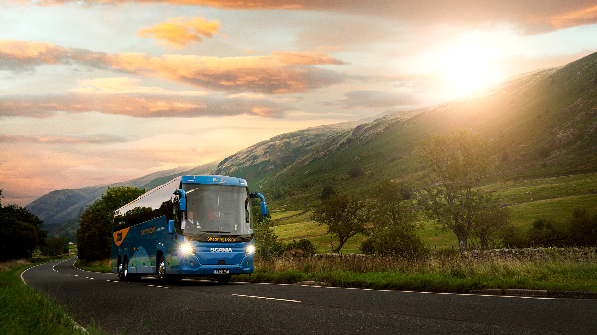 Cinematic photograph of a coach travelling through the mountains at sunset. 