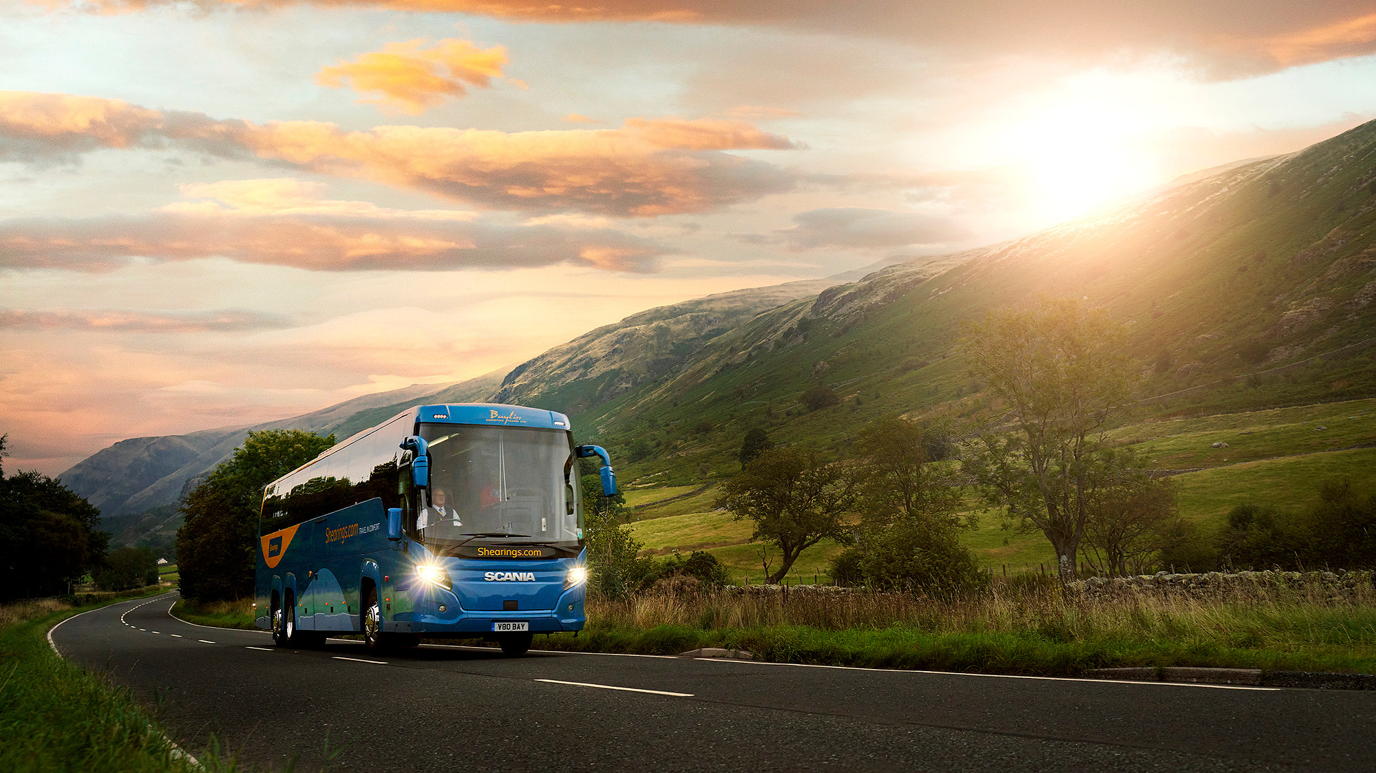 Cinematic photograph of a coach travelling through the mountains at sunset. 