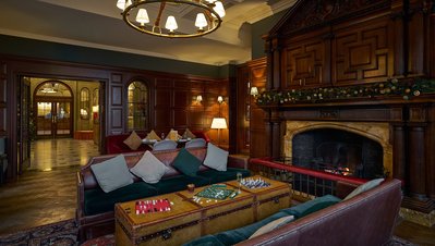 A dark and moody hotel library with comfy sofas and a fire place. 