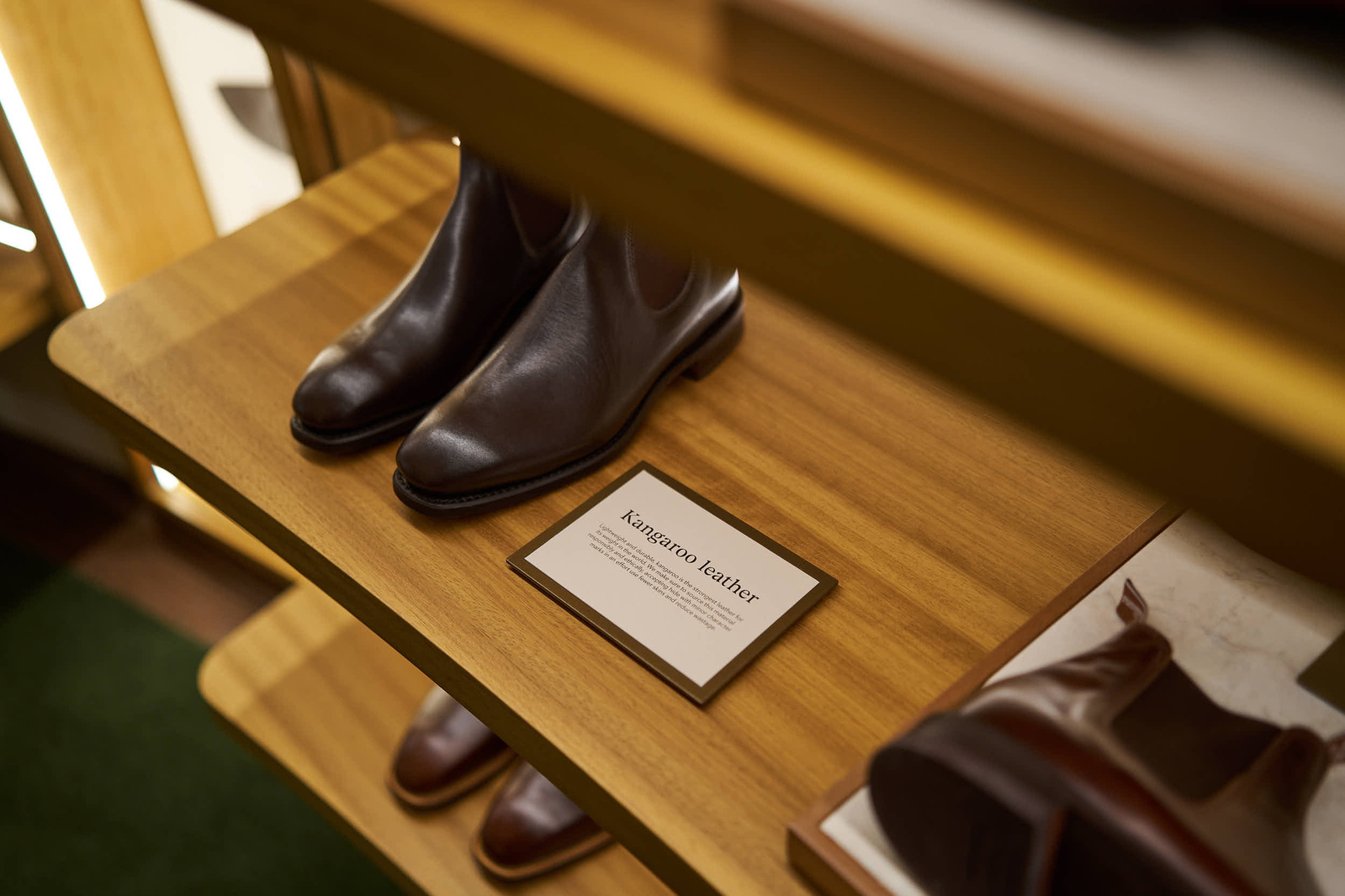 a pair of brown leather boots on a wooden shelf