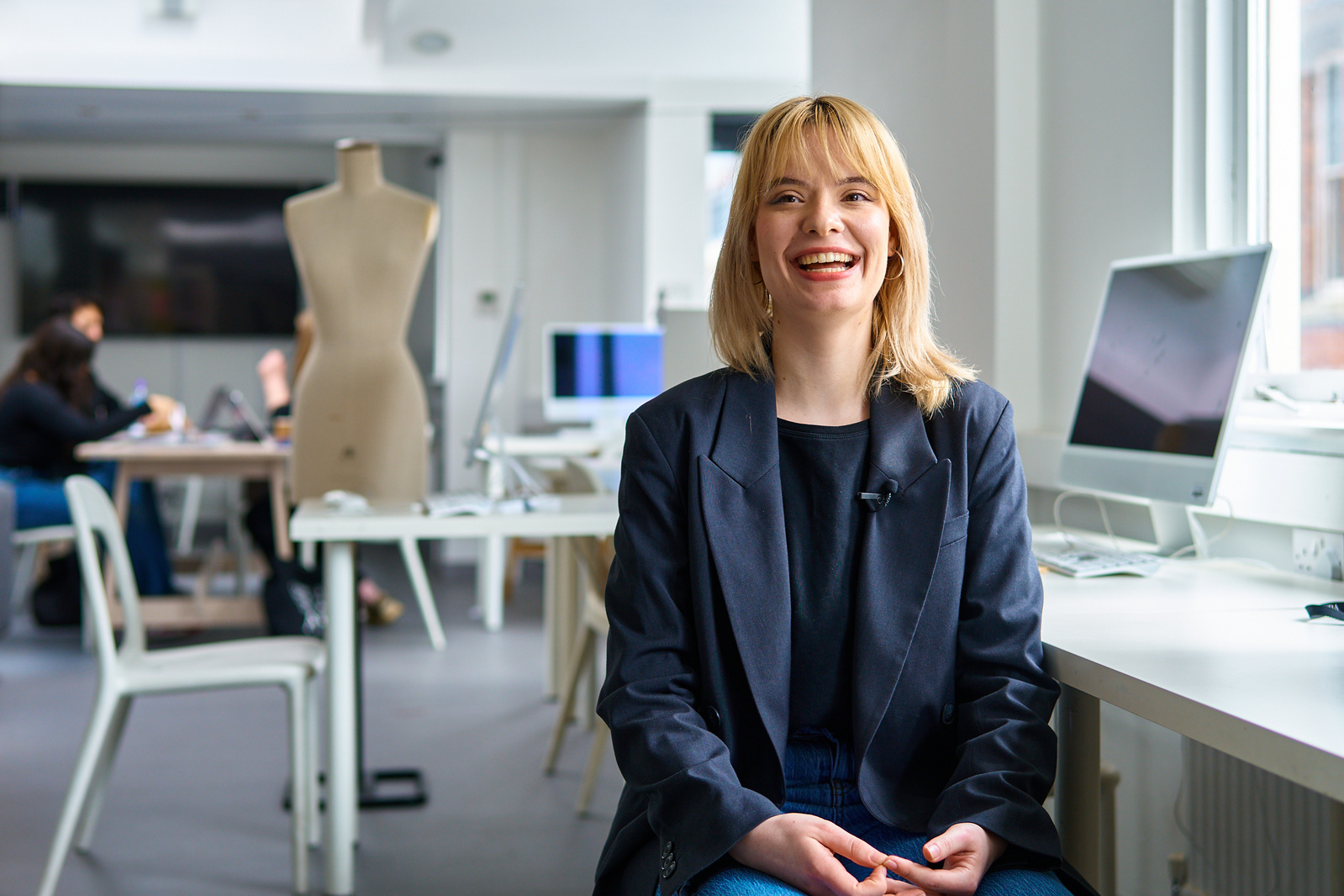 University student in front of a computer smiling at the camera. 
