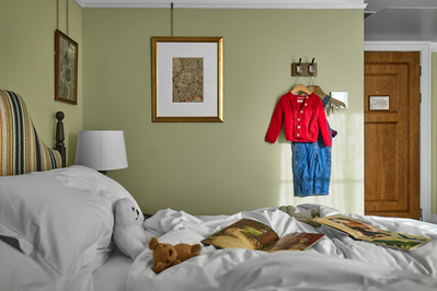 A bright and airy hotel room interior photograph with children's clothes and toys. 