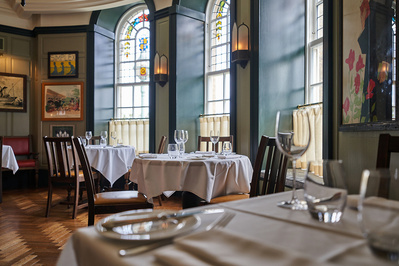 A bright and airy hotel restaurant with evening sun coming through the windows. 