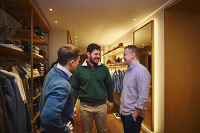 three people talking in a menswear store. 