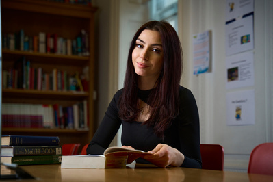 Female student poses for portrait in a dark library
