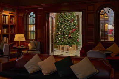 A dark and moody photograph of a Christmas tree in a hotel lobby, shot through a door way. 
