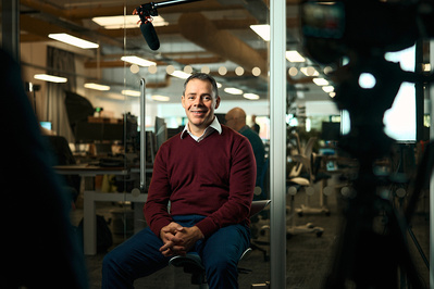 A cinematic portrait of an office worker in his office being interviewed. 
