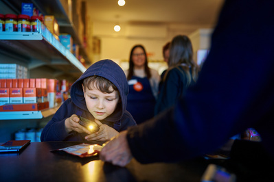 a young boy scans an item in a small grocery shop. 