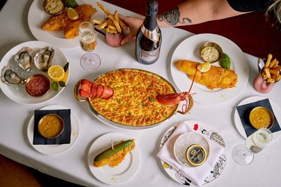 A top down shot of a seafood platter in a restaurant. The food is on a white table cloth and the centre piece is a lobster dish. 