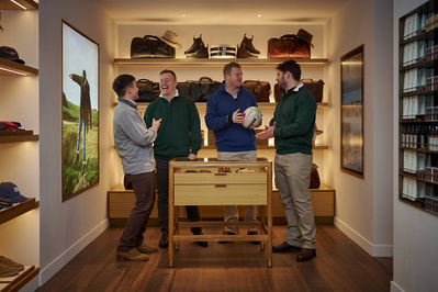 Four people standing in front of a display of shoes in a menswear shop. 