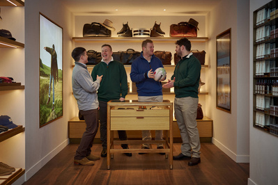 Four people standing in front of a display of shoes in a menswear shop. 