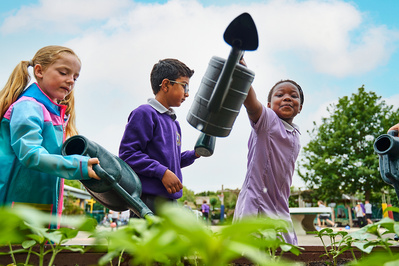 Three young students watering plants