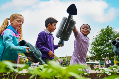 Three young students watering plants