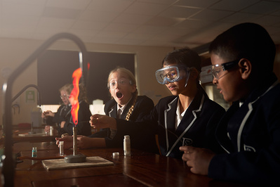 Four school children conducting a science experiment in class with a flame  